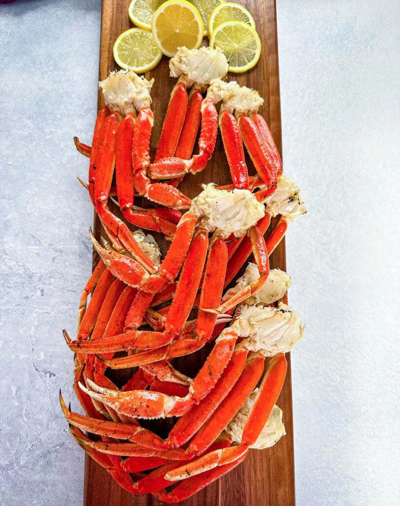 grilled snow crab legs on a wooden board with lemon