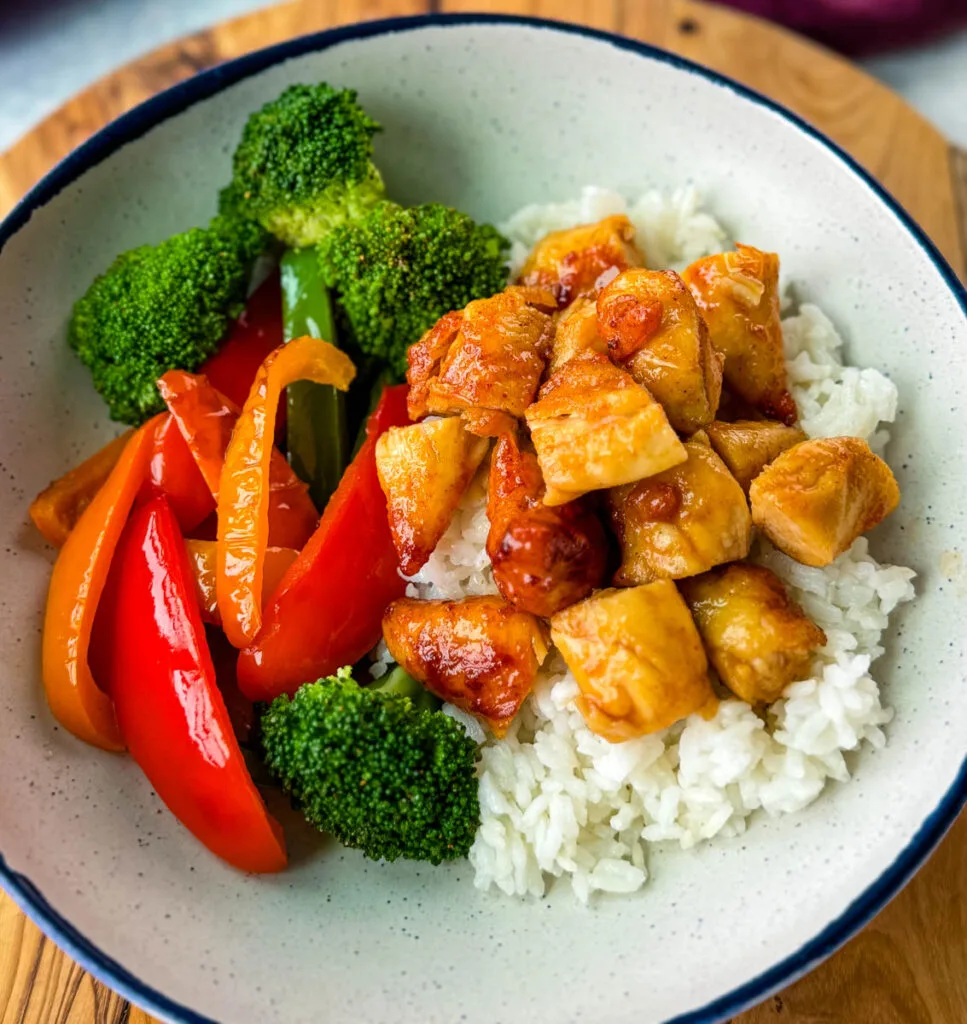 hot honey chicken, rice, broccoli, and bell pepper vegetables in a white bowl