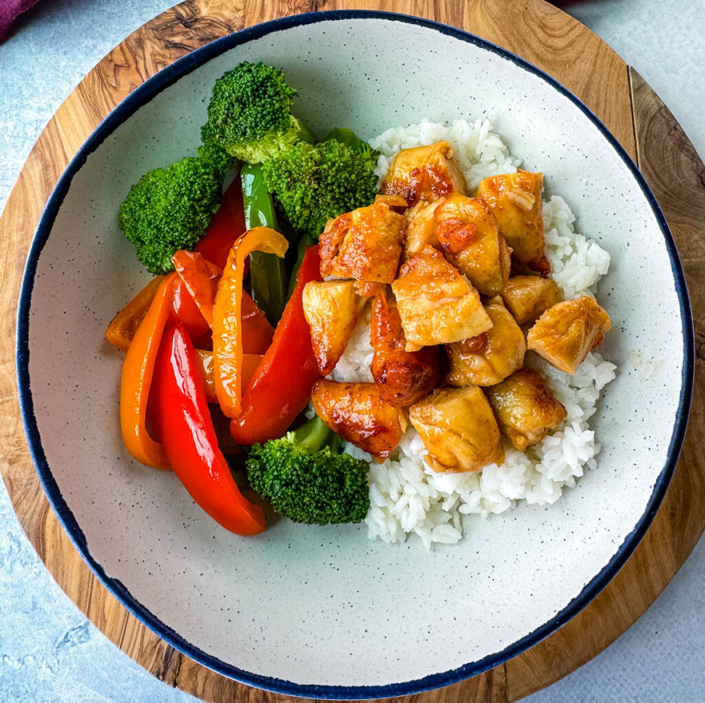 hot honey chicken, rice, broccoli, and bell pepper vegetables in a white bowl