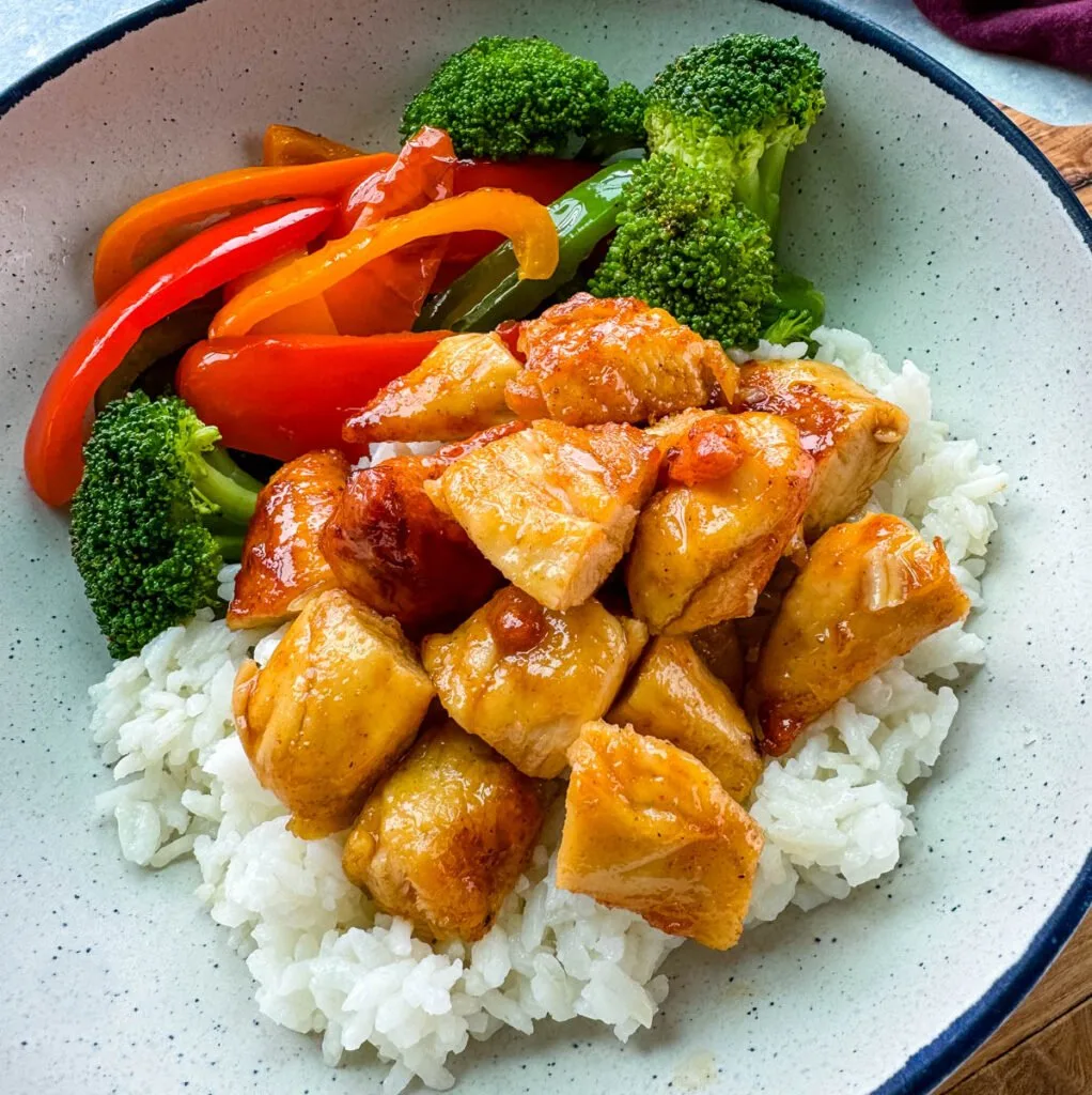 hot honey chicken, rice, broccoli, and bell pepper vegetables in a white bowl