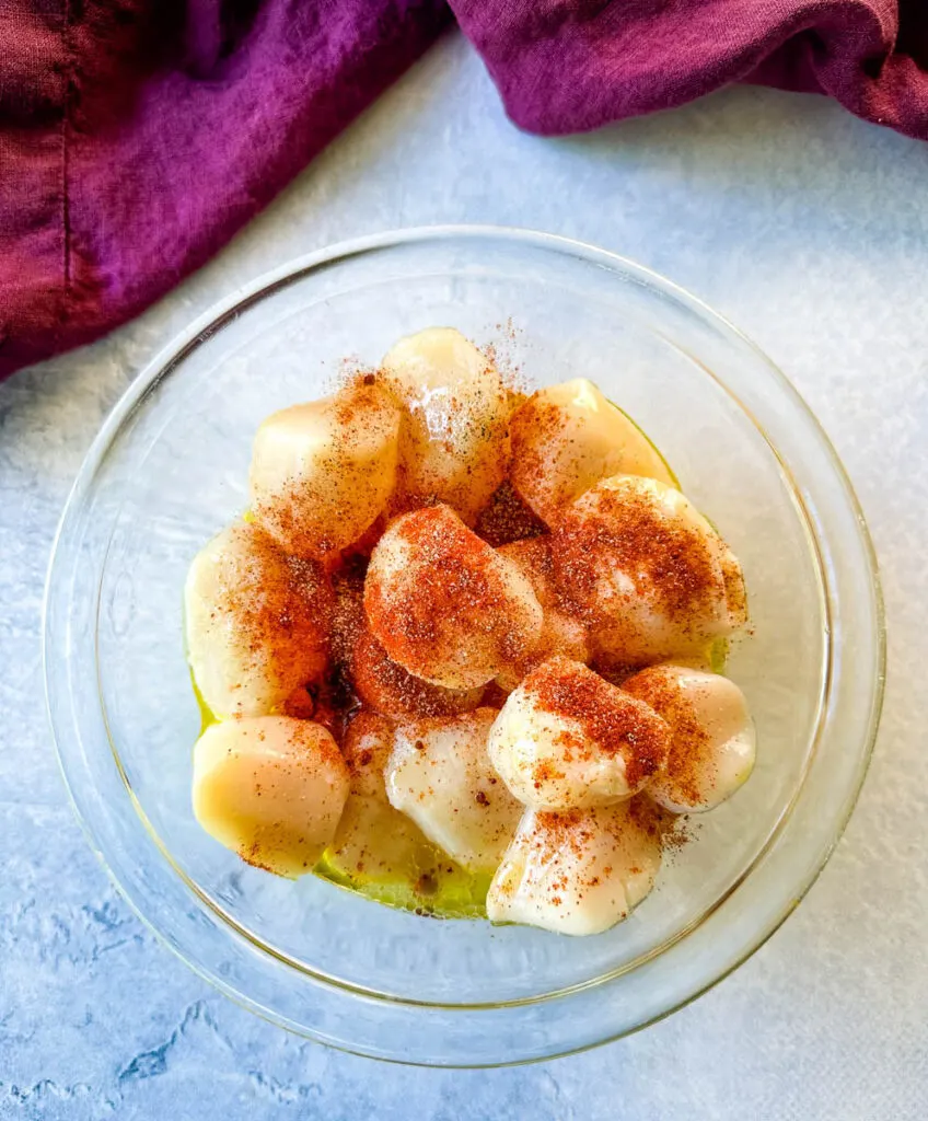 raw seasoned scallops in a glass bowl