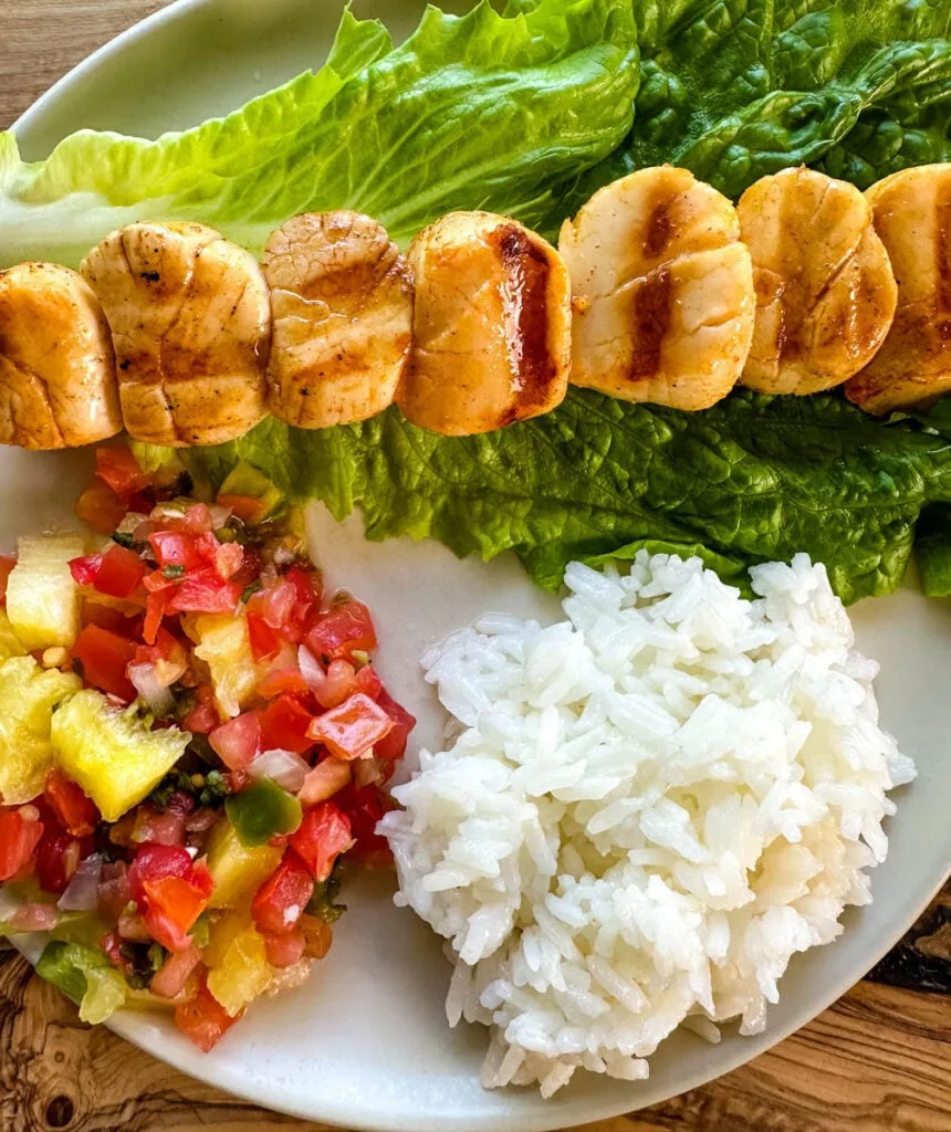 grilled scallops on a plate with lettuce, rice, and vegetables