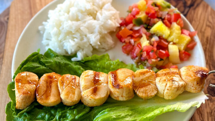 grilled scallops on a plate with lettuce, rice, and vegetables