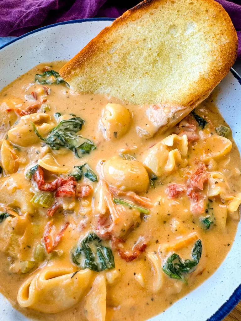 marry me Tuscan chicken soup in a white bowl with a piece of bread