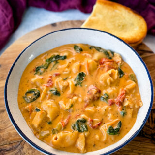 marry me Tuscan chicken soup in a white bowl with a piece of bread