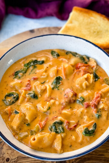 marry me Tuscan chicken soup in a white bowl with a piece of bread