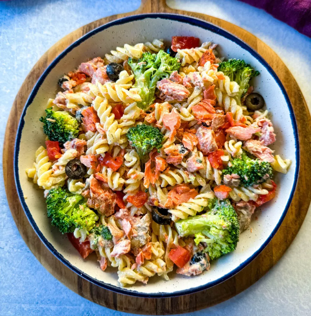 salmon pasta salad with broccoli and tomatoes in a white bowl