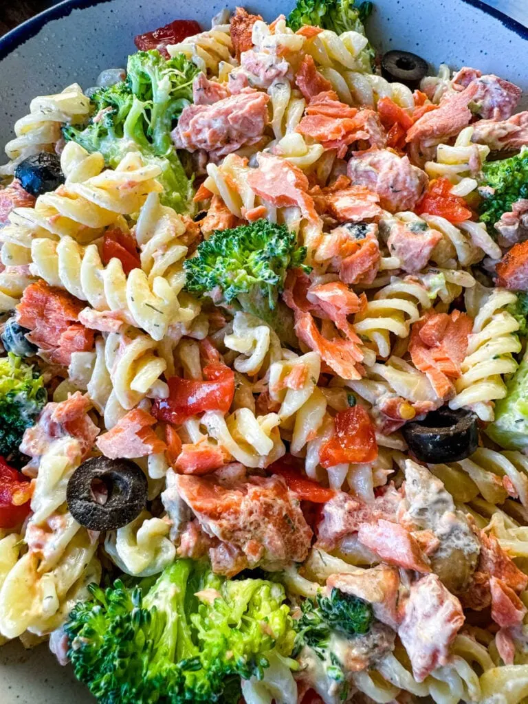 salmon pasta salad with broccoli and tomatoes in a white bowl