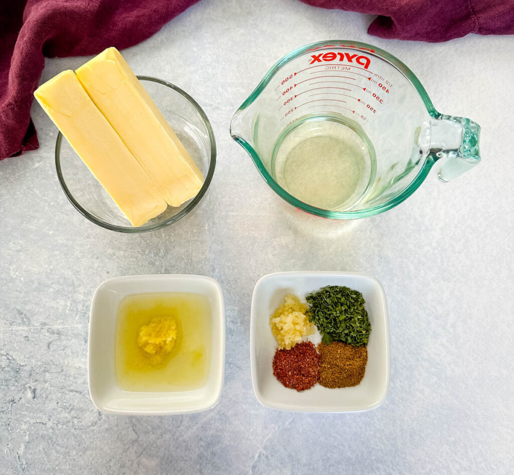 sticks of butter, white wine, garlic, and spices in separate bowls