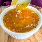 seafood boil garlic butter sauce in a white bowl with a spoon