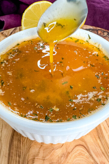 seafood boil garlic butter sauce in a white bowl with a spoon