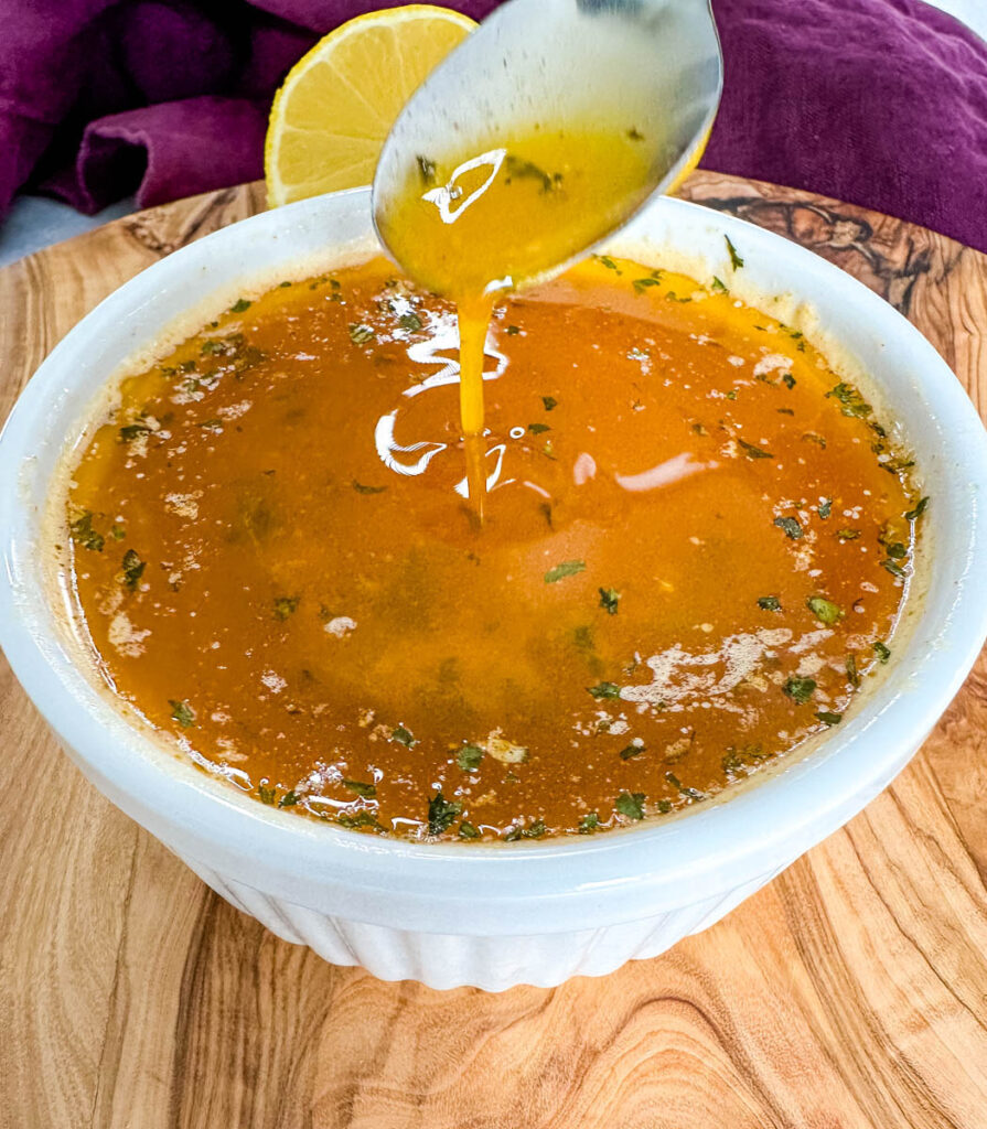 seafood boil garlic butter sauce in a white bowl with a spoon