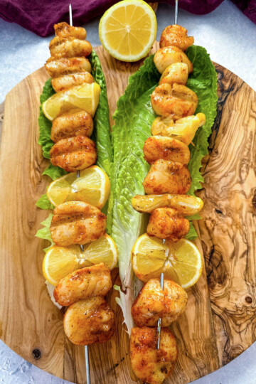 smoked scallops on skewers on a bed of lettuce with lemons