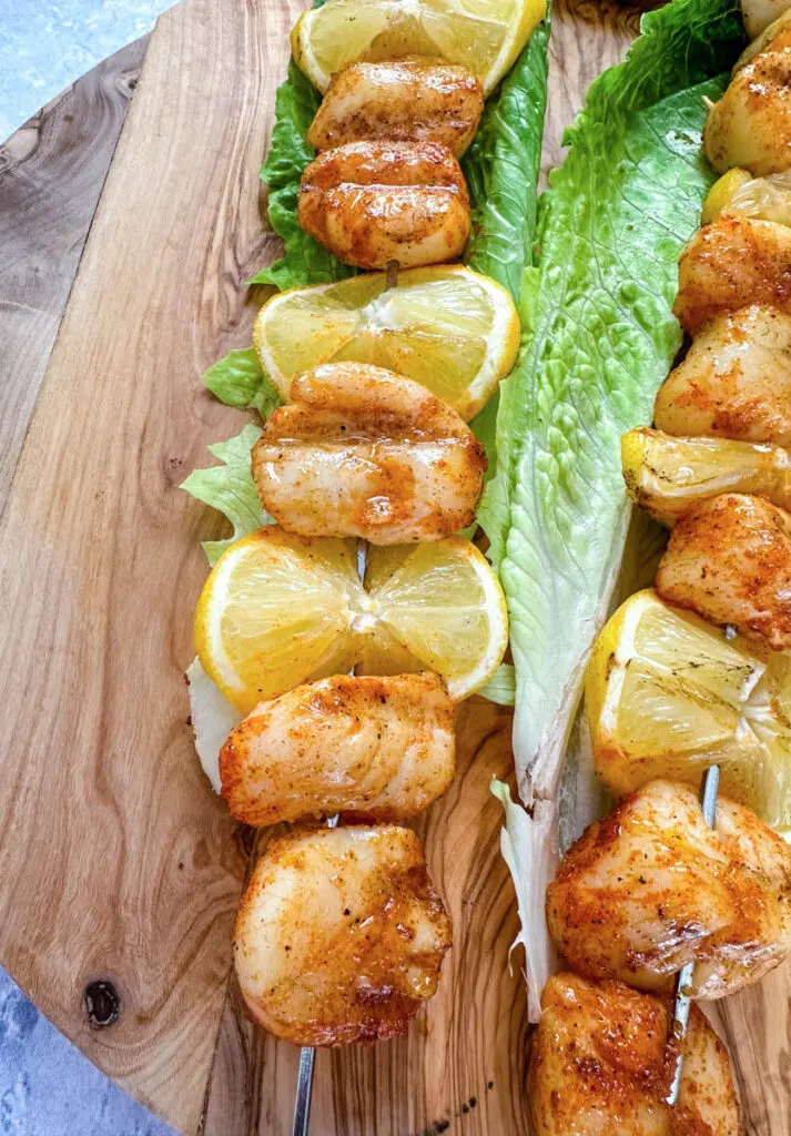 smoked scallops on skewers on a bed of lettuce with lemons