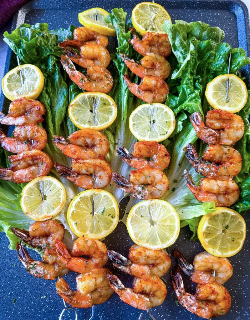 smoked shrimp on skewers with lemon on a bed of lettuce