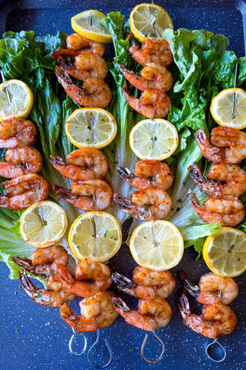 smoked shrimp on skewers with lemon on a bed of lettuce