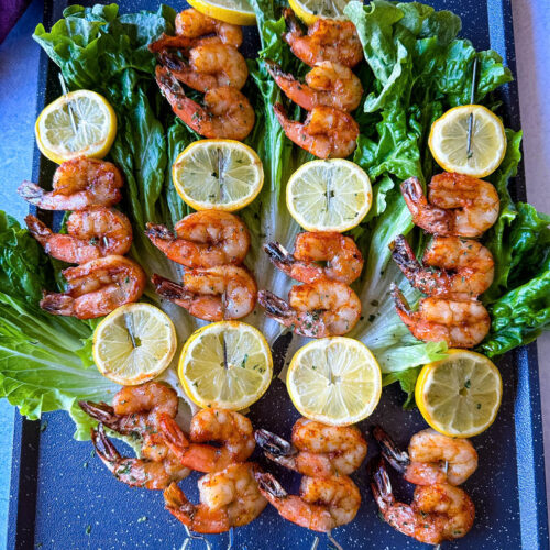 smoked shrimp on skewers with lemon on a bed of lettuce