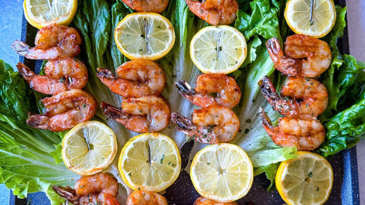 smoked shrimp on skewers with lemon on a bed of lettuce