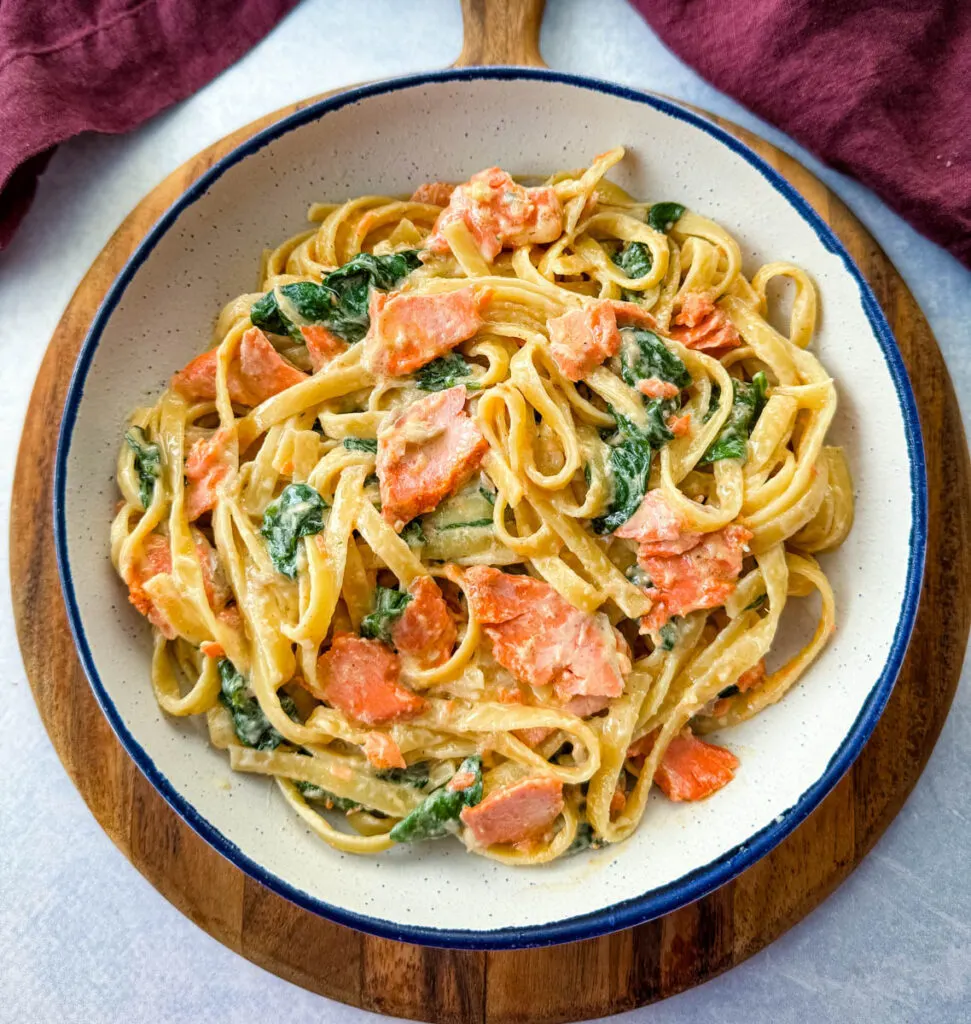 salmon Fettuccine Alfredo with spinach in a white bowl