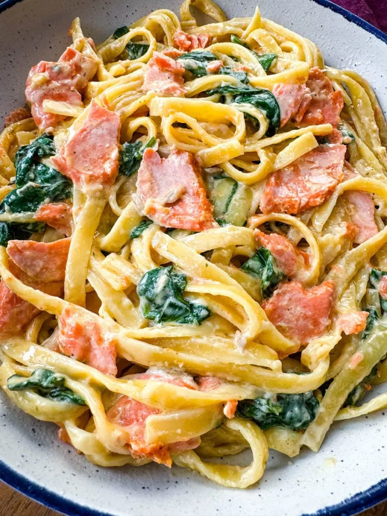 salmon Fettuccine Alfredo with spinach in a white bowl