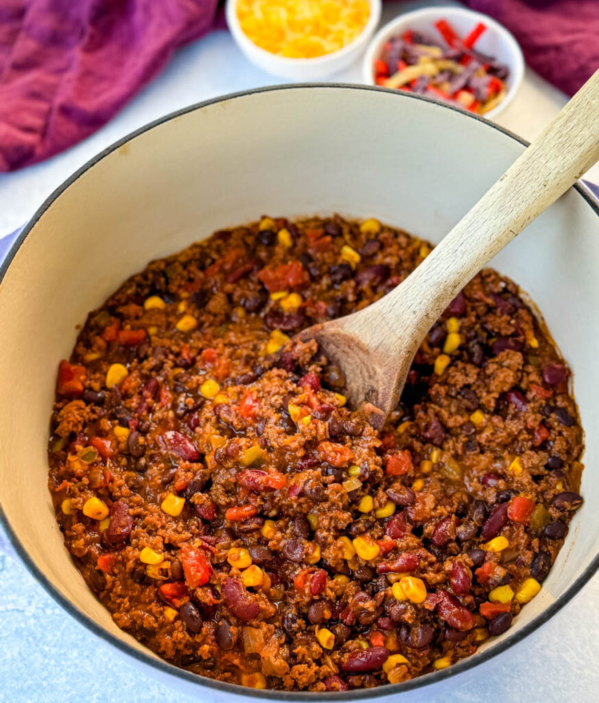 beef taco chili in a Dutch oven with a wooden spoon