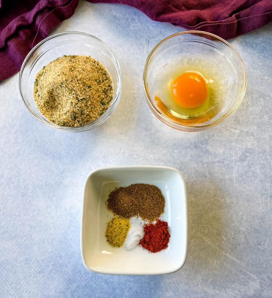 breadcrumbs, raw eggs, and spices in separate glass bowls