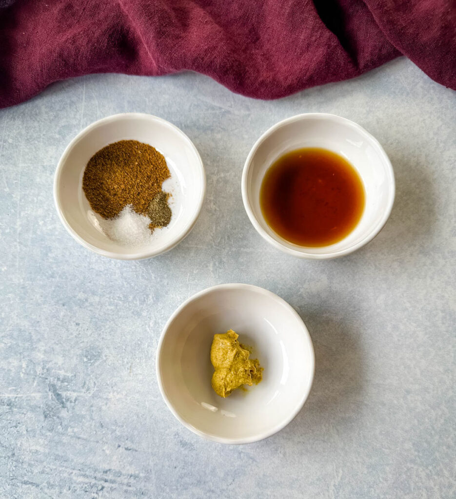 Old Bay seasoning, hot sauce, and mustard in separate white bowls