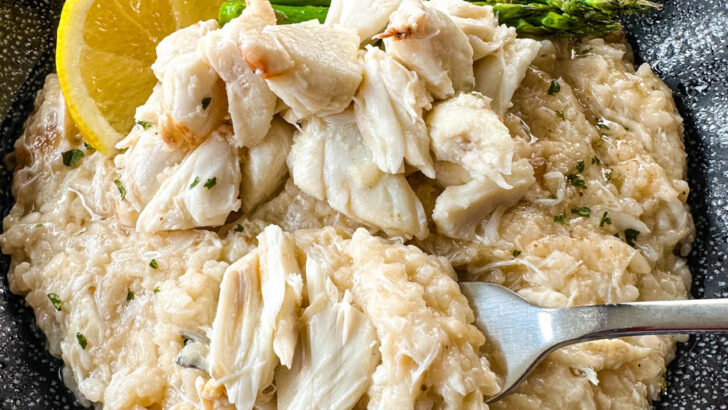 crab risotto in a black bowl with fresh lemon and asparagus