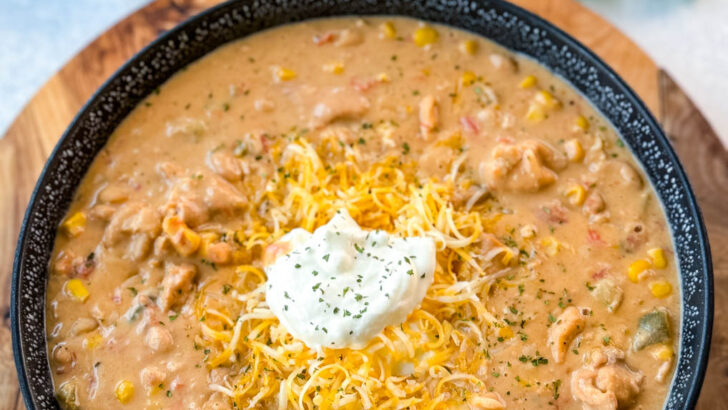 white chicken chili in a black bowl with sour cream and grated cheese