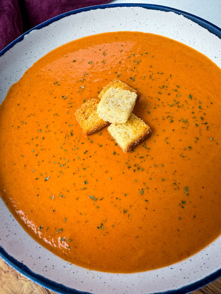 homemade creamy tomato soup in a white bowl with croutons