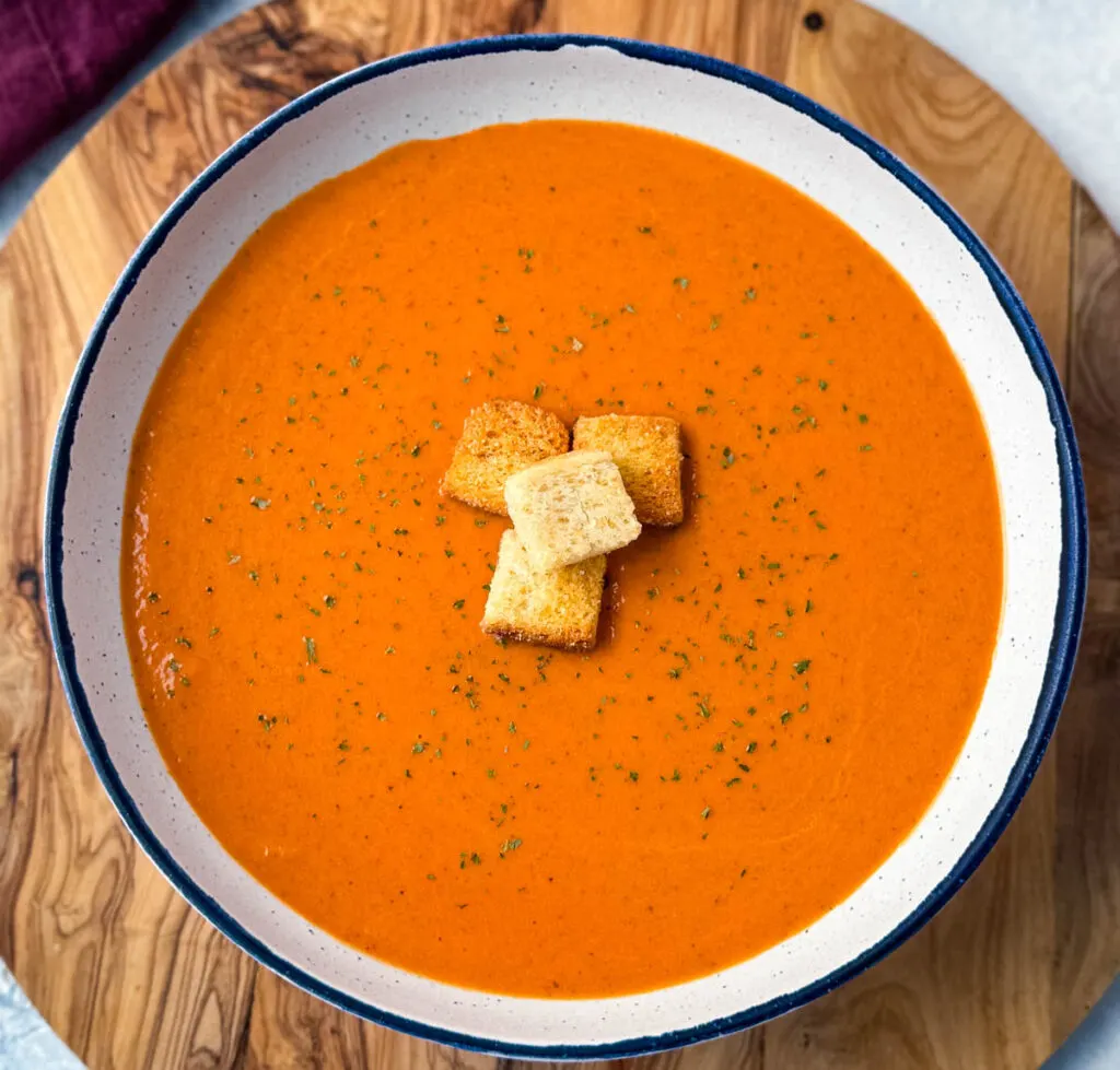 homemade creamy tomato soup in a white bowl with croutons