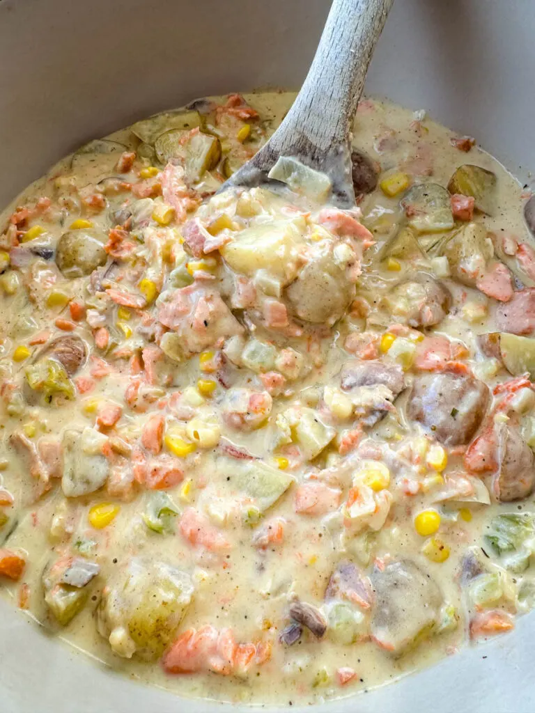 creamy salmon chowder with corn and potatoes in a Dutch oven