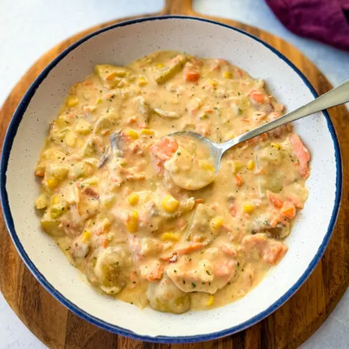 creamy salmon chowder with corn and potatoes in a white bowl with a spoon