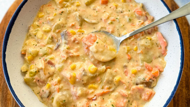 creamy salmon chowder with corn and potatoes in a white bowl with a spoon