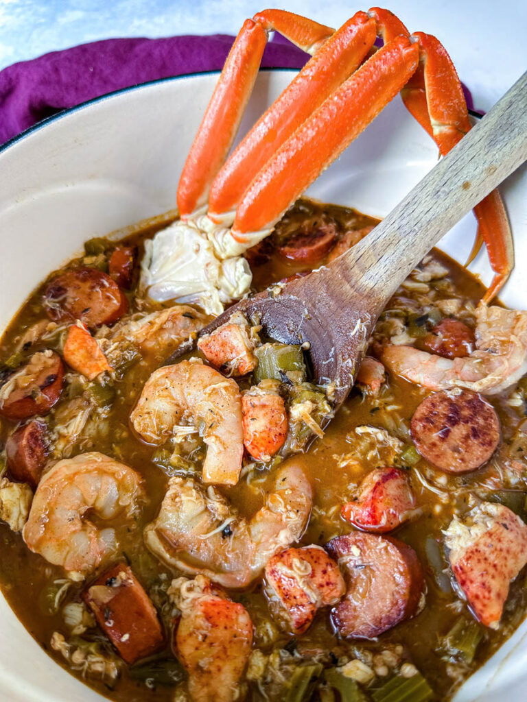 Cajun seafood gumbo with shrimp and crab meat and crab legs with rice in a Dutch oven with a wooden spoon