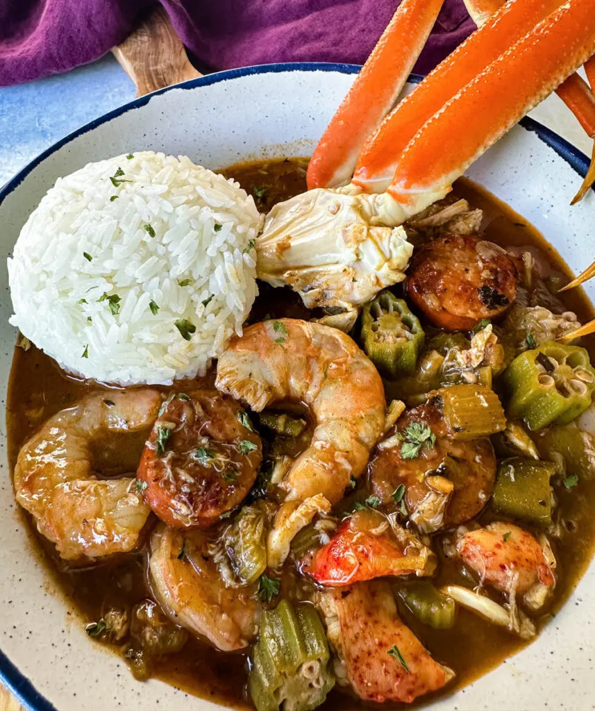 Cajun seafood gumbo with shrimp and crab meat and crab legs with rice in a white bowl