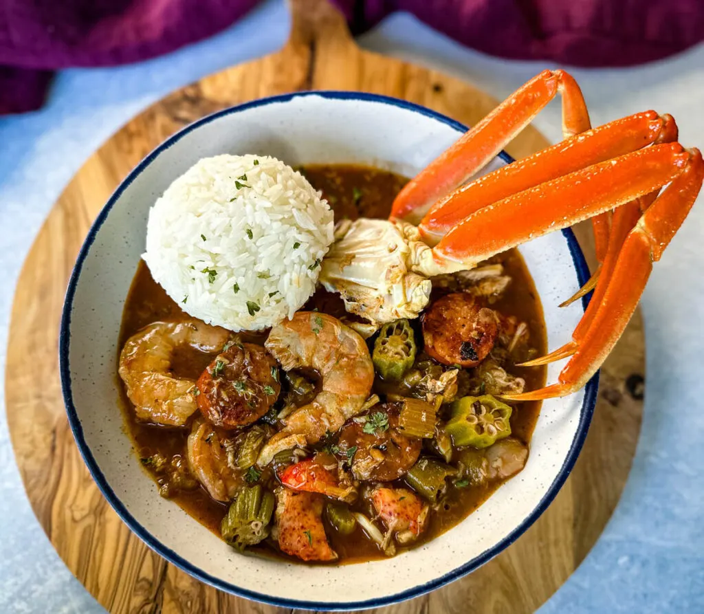 Cajun seafood gumbo with shrimp and crab meat and crab legs with rice in a white bowl