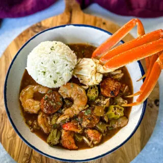 Cajun seafood gumbo with shrimp and crab meat and crab legs with rice in a white bowl