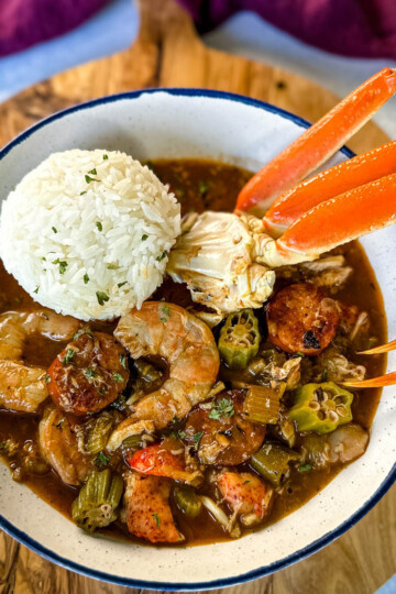 Cajun seafood gumbo with shrimp and crab meat and crab legs with rice in a white bowl