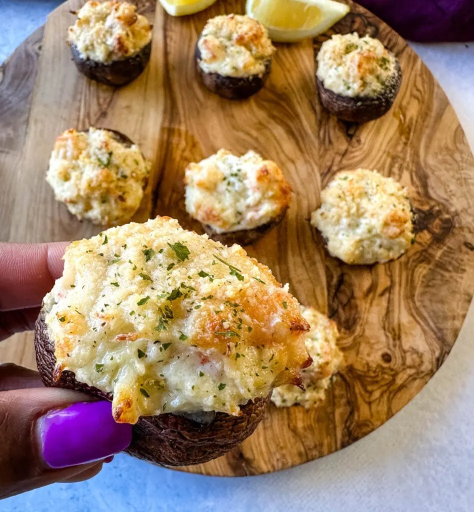 person holding baked seafood stuffed mushroom