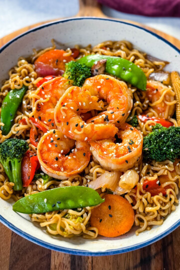 shrimp stir fry with noodles, vegetables, and a homemade sauce in a white bowl