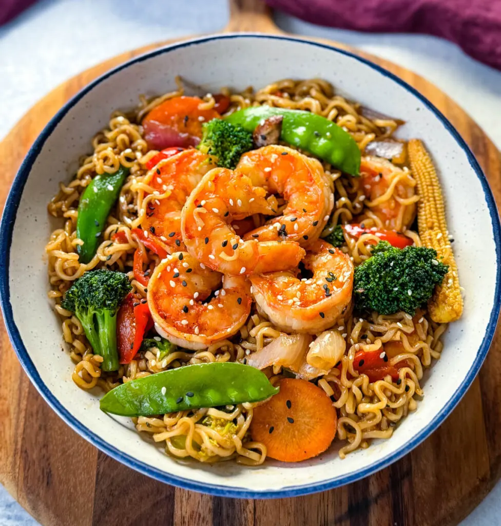 shrimp stir fry with noodles, vegetables, and a homemade sauce in a white bowl