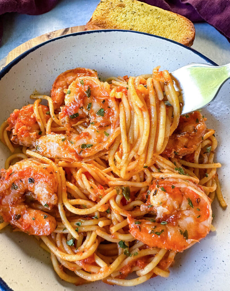 shrimp spaghetti with garlic in a white bowl with a fork