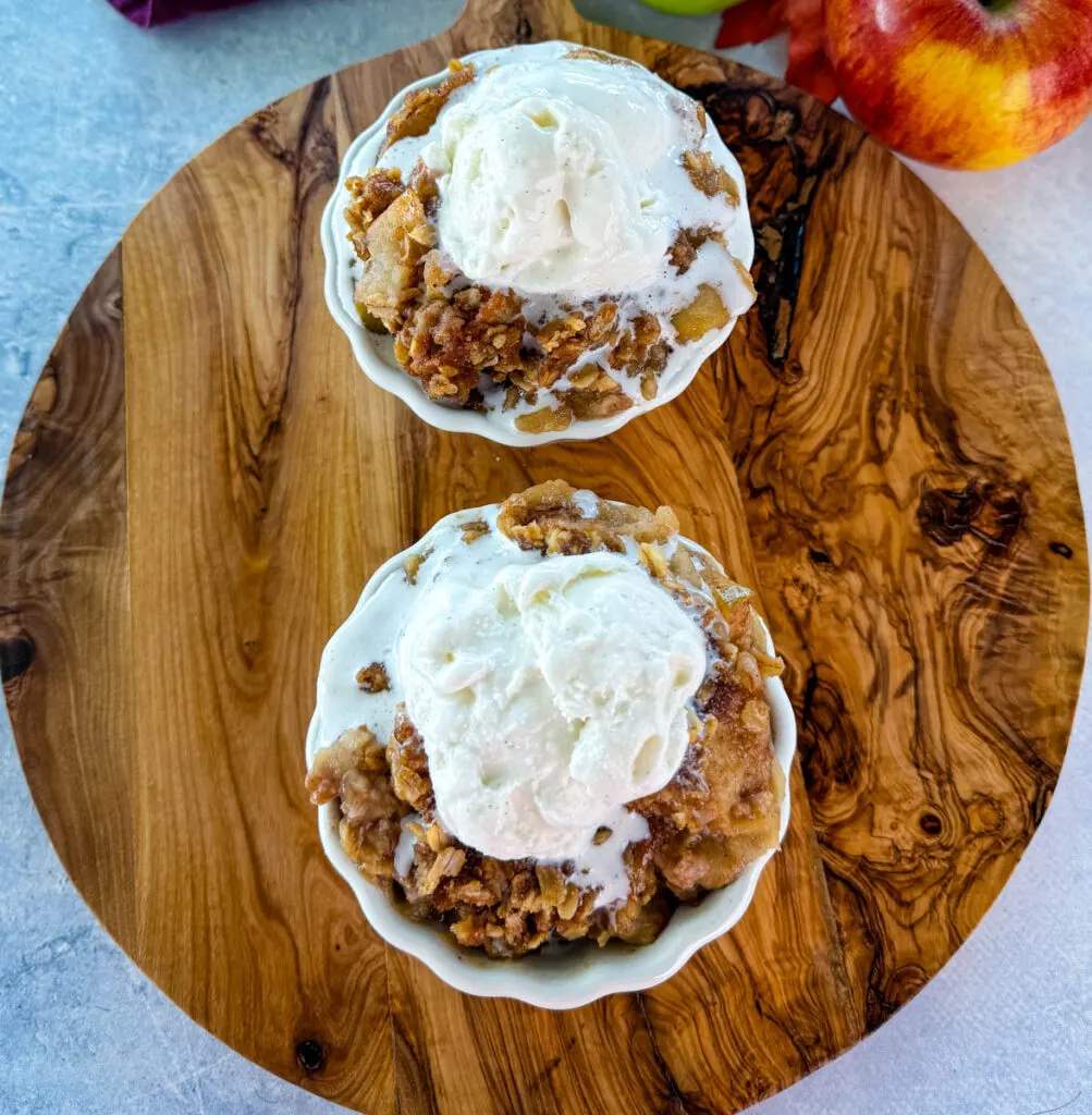 slow cooker Crockpot apple crisp in a white bowl with a scoop of vanilla ice cream