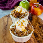 slow cooker Crockpot apple crisp in a white bowl with a scoop of vanilla ice cream and caramel