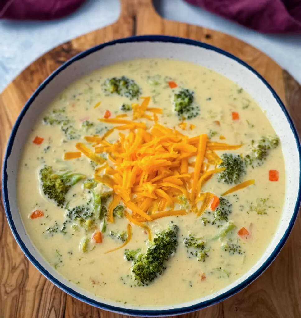 broccoli cheddar soup in a white bowl with grated cheddar cheese