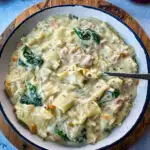 white lasagna soup in a bowl with carrots, celery, and spinach