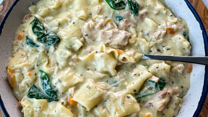 white lasagna soup in a bowl with carrots, celery, and spinach