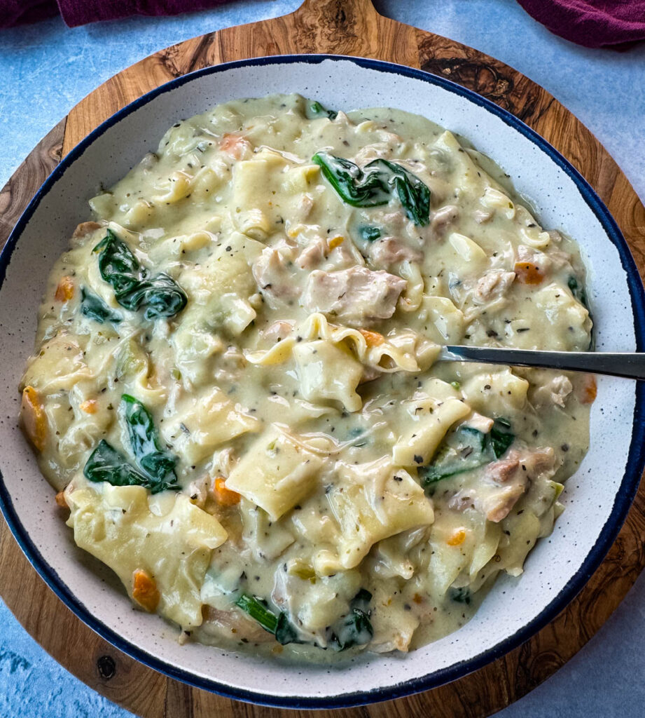 white lasagna soup in a bowl with carrots, celery, and spinach