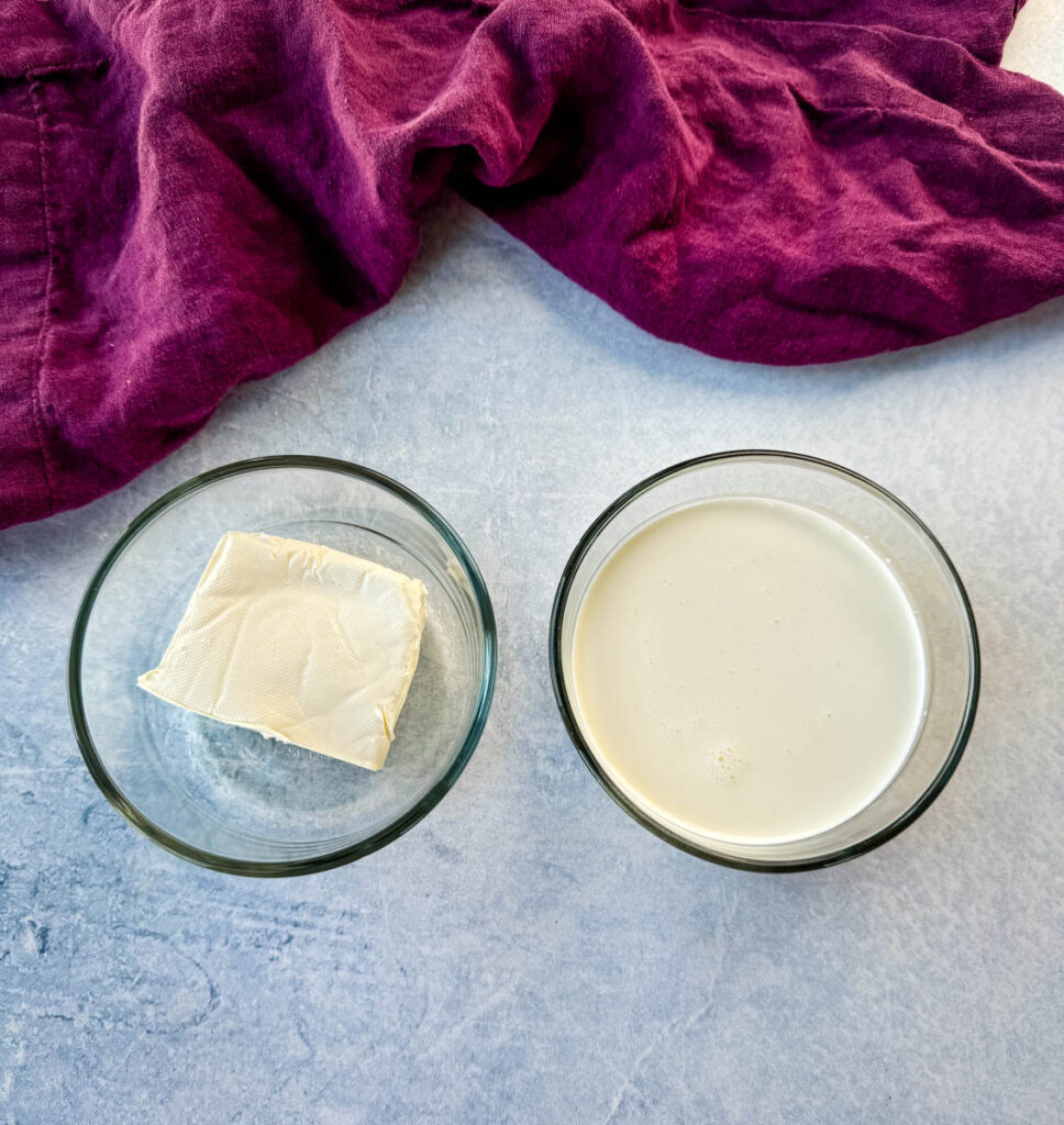cream cheese and heavy whipping cream in separate glass bowls